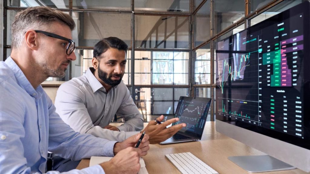 دو مرد پشت میز در کنار یکدیگر نشسته اند و مشغول کار هستند - شغل پر درآمد با سرمایه کم برای آقایان